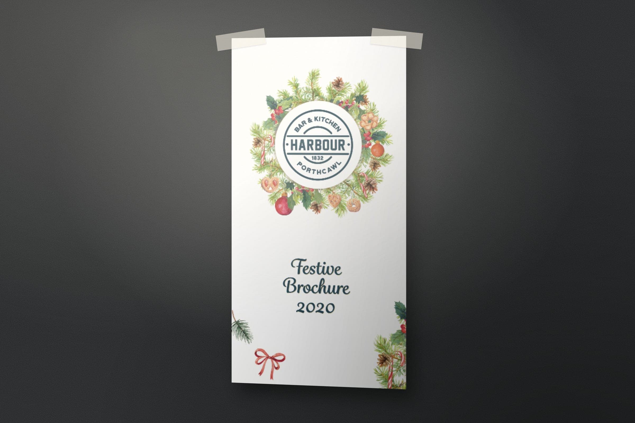 Mockup: the Harbour Bar & Kitchen festive brochure 2020 cover, the roundel in a winter wreath.