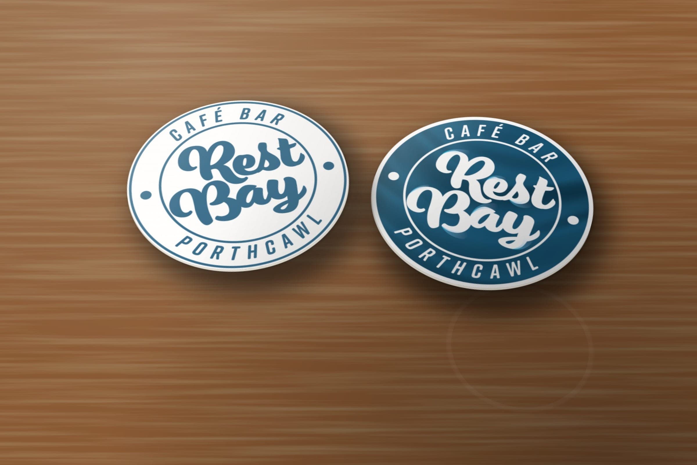 Mockup: Rest Bay Café Bar round beermats, the outline roundel on one side and the solid blue roundel on the other.